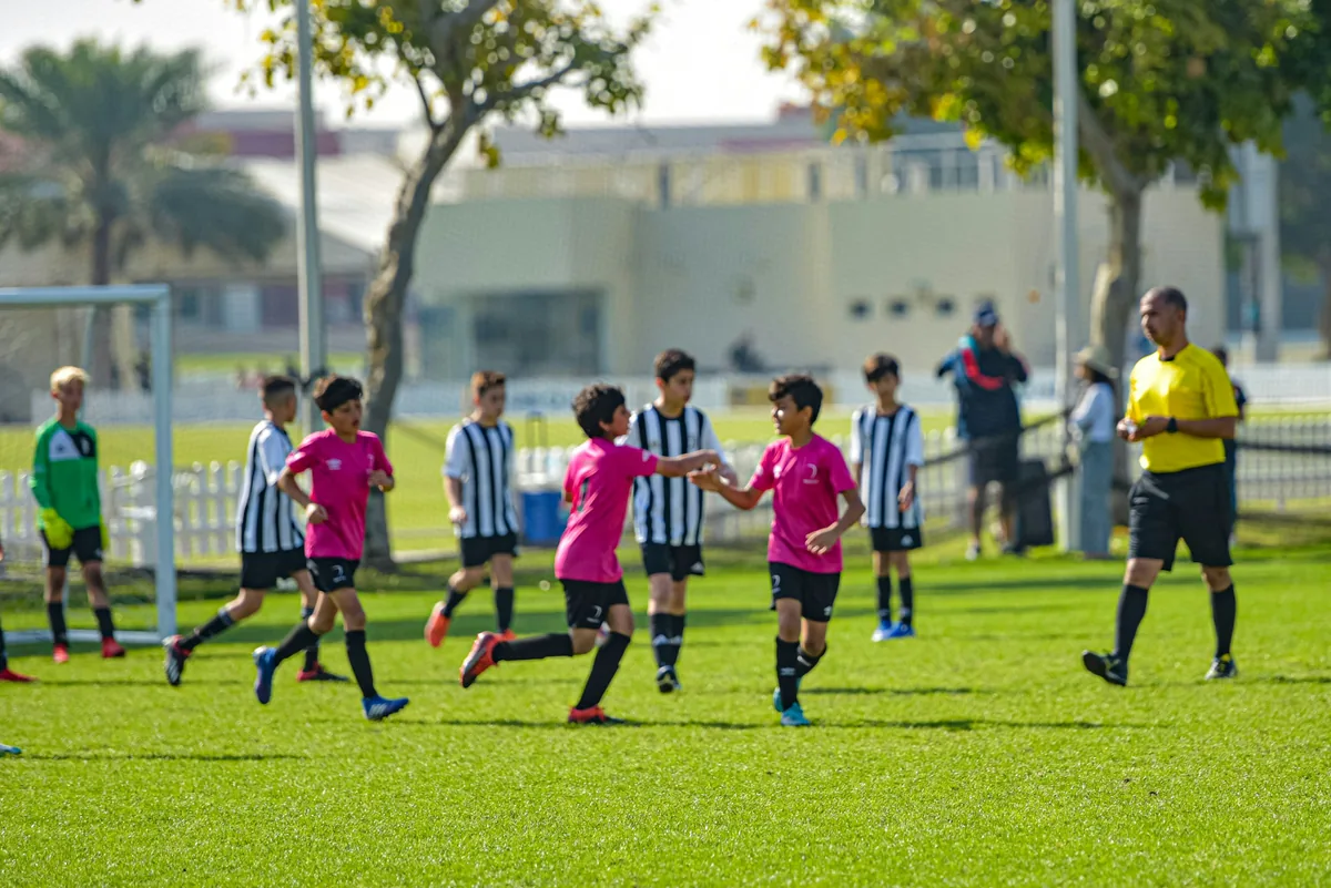 Young footballers in red and white kit playing a match on a grass pitch