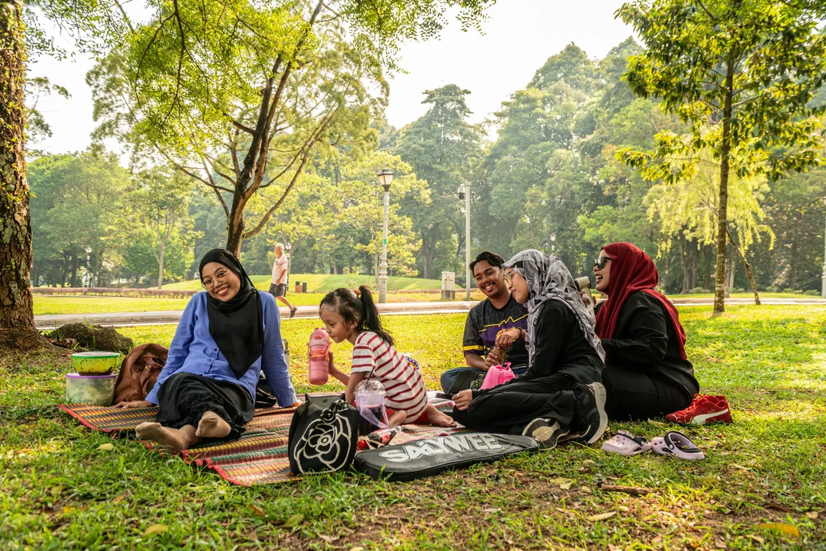 Families sitting together on picnic mats in a sunlit park