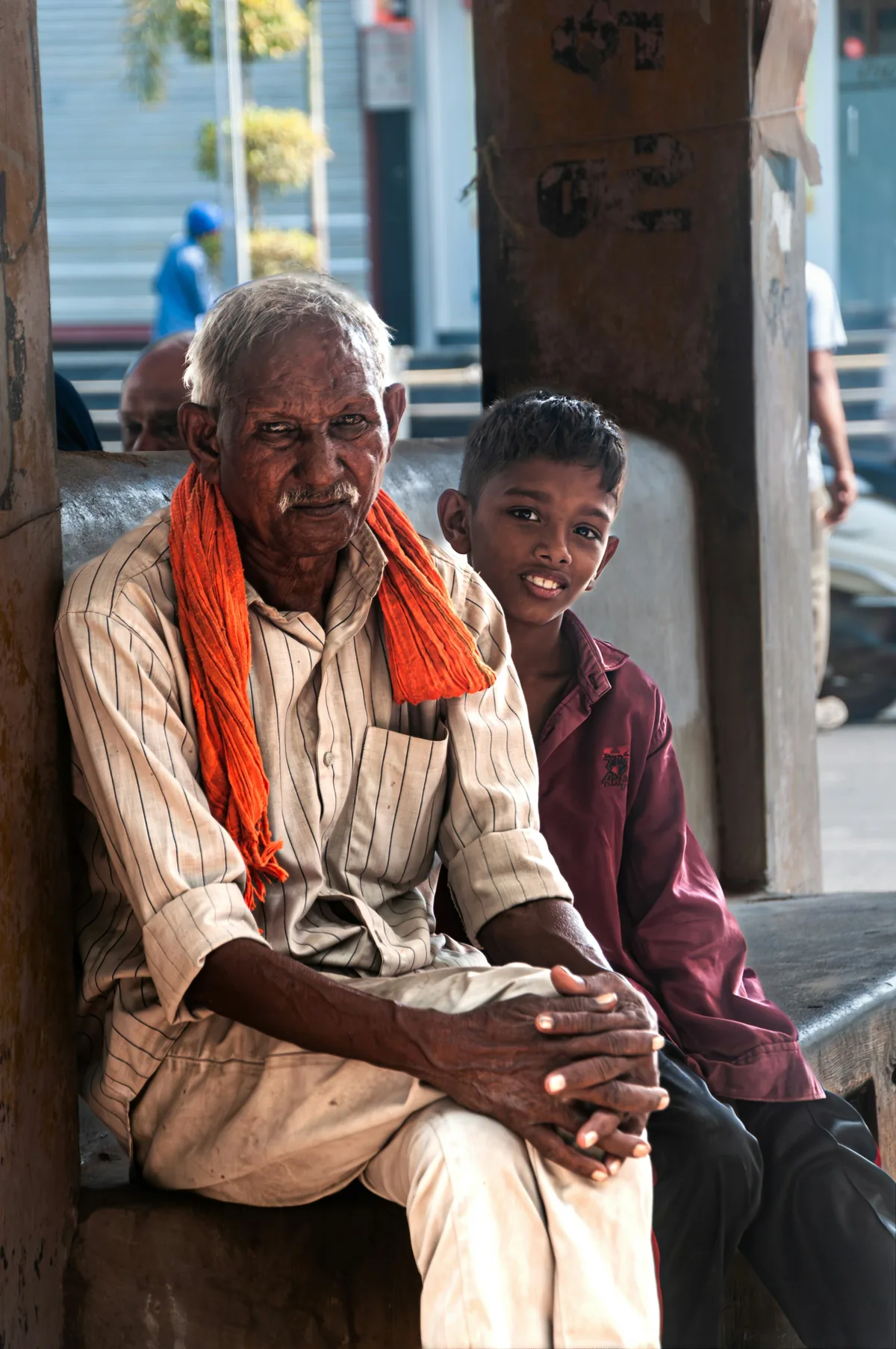 An elderly man and a young boy sitting together, smiling