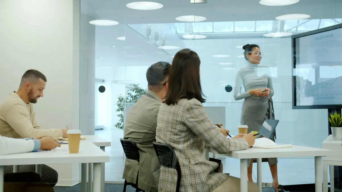 A woman leader speaking with a small team in a bright, modern office