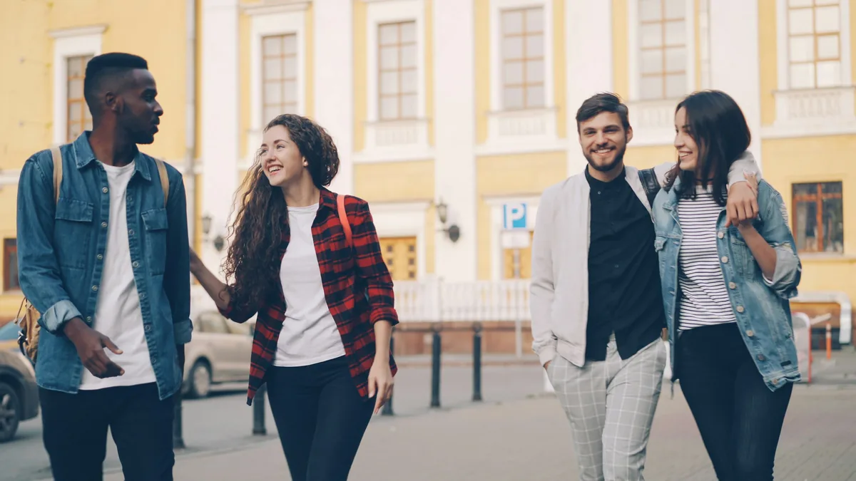 Four young friends walking and smiling together outdoors